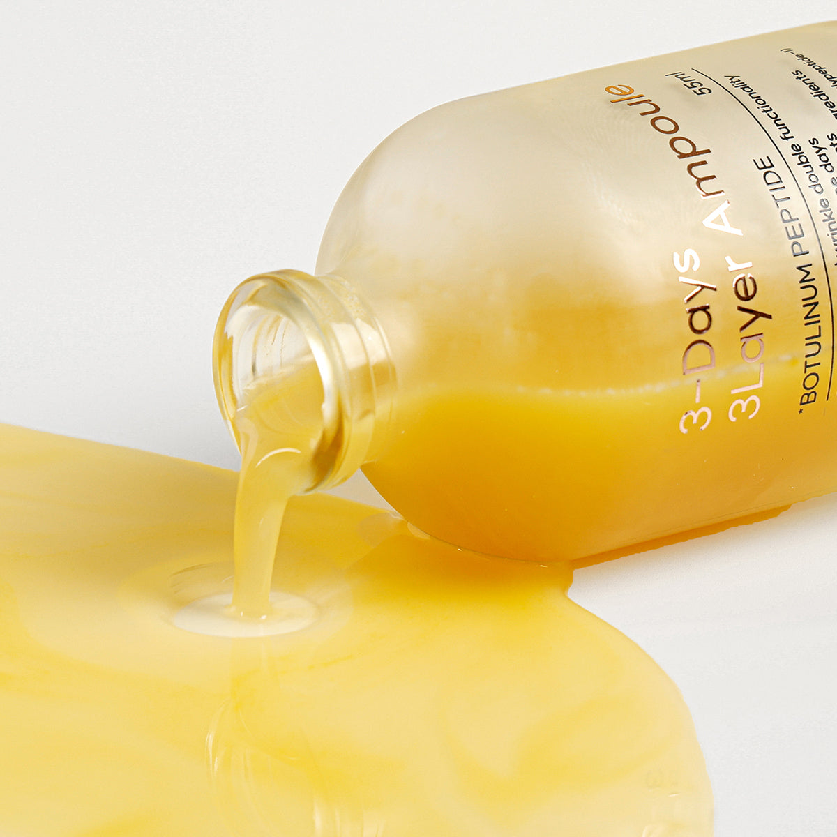 Skincare bottle with yellow liquid spilling out on a white background