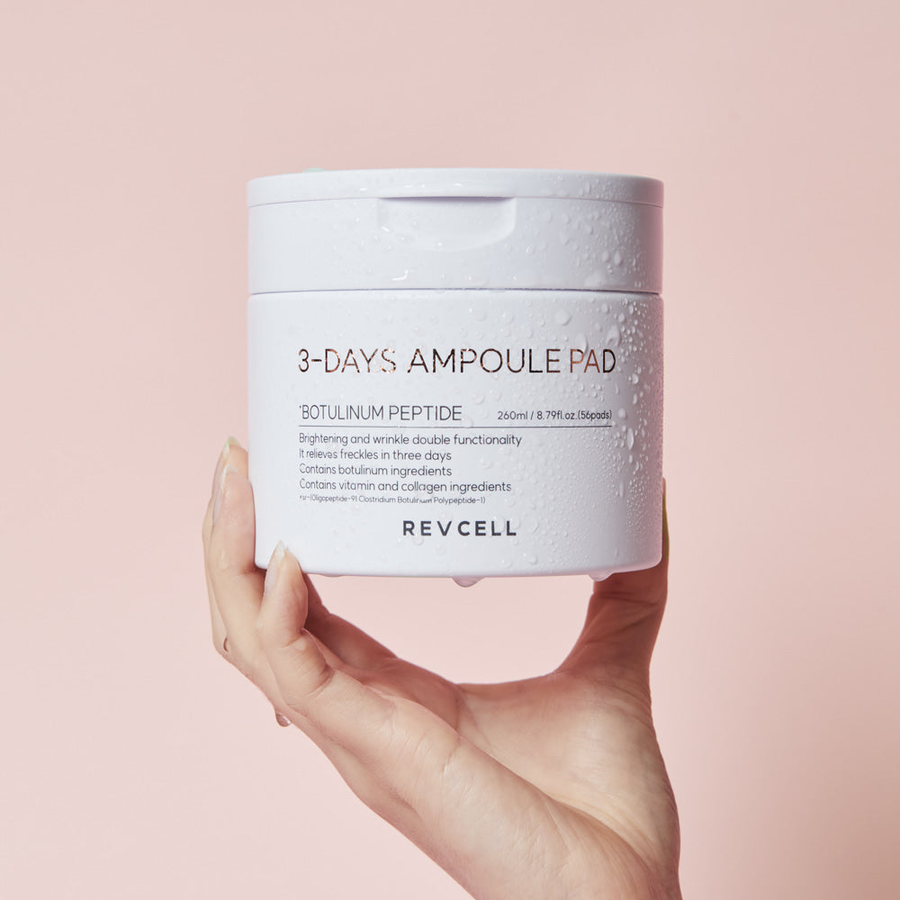 Hand holding a jar of Revcell 3-Days Ampoule Pad against a pink background